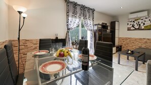 Un comedor moderno con una mesa de vidrio, sillas negras y una botella de vino.