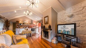 Un soggiorno accogliente con camino, un televisore che mostra 'GuestReady' e una cucina sullo sfondo.