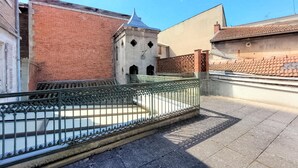 Een binnentuin met een bakstenen gebouw, een kleine toren en een metalen hek.