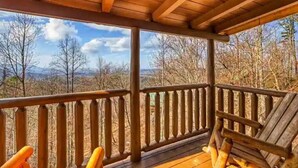 Une terrasse en bois dotée d’une rambarde, offrant une vue sur un paysage boisé.