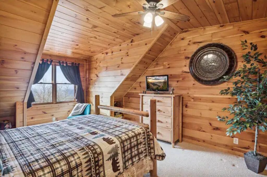 Un dormitorio acogedor con cama, ventilador de techo, cómoda y ventana con cortinas.