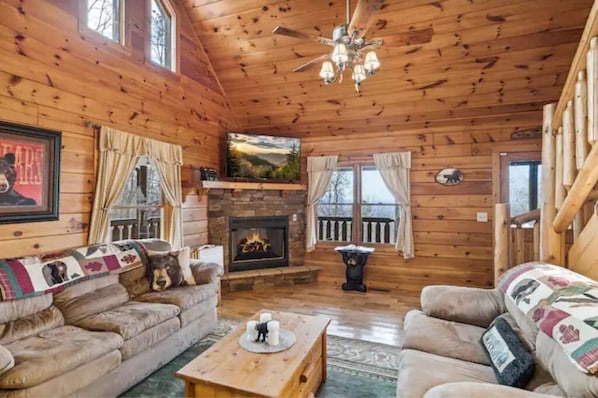 A cozy cabin interior with a fireplace, wooden walls, and a comfortable seating area. - Mountain views, HUGE theater room, hot tub, game room! (Sevierville)