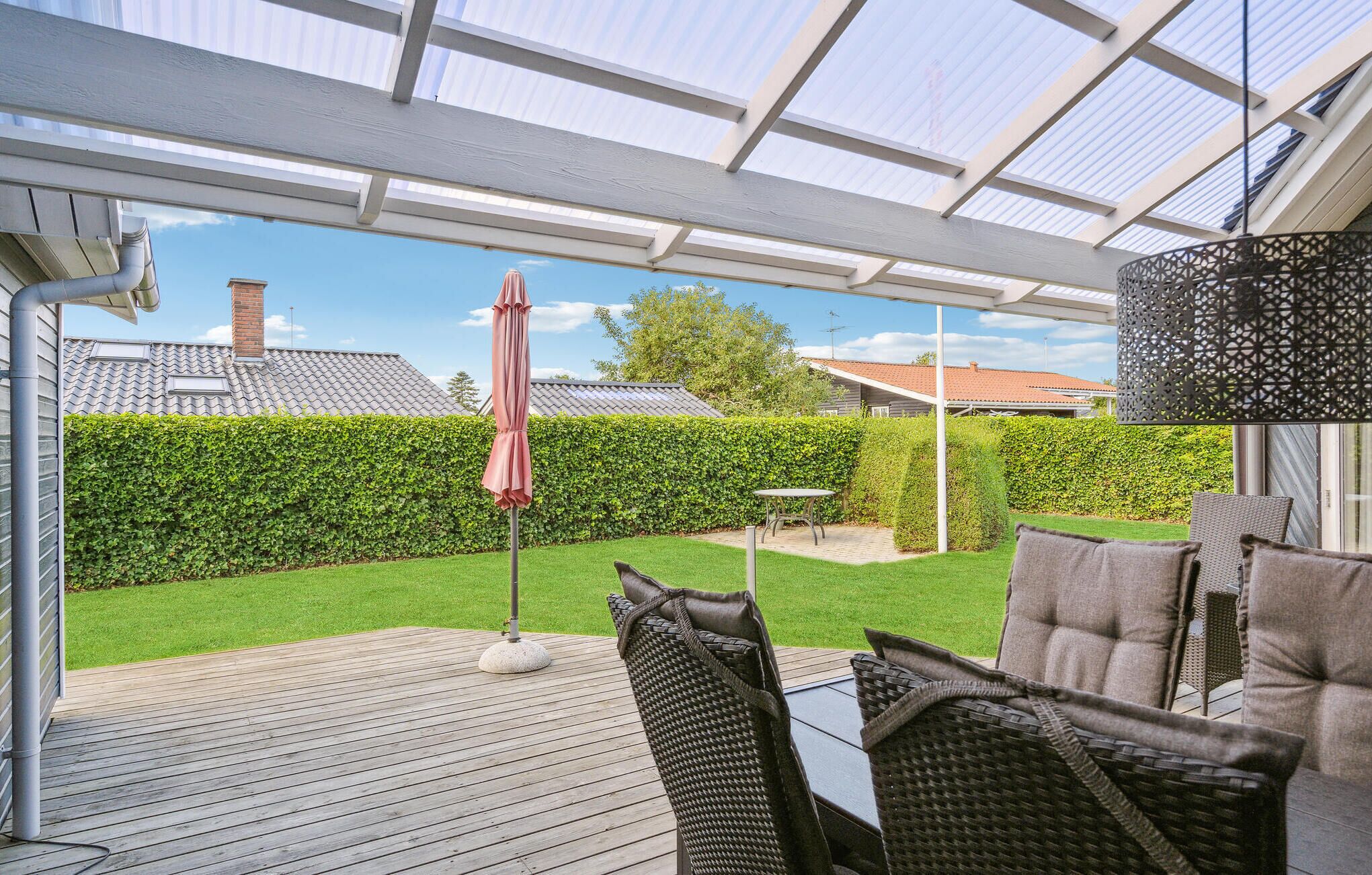 A covered patio with outdoor furniture, a table, and an umbrella.