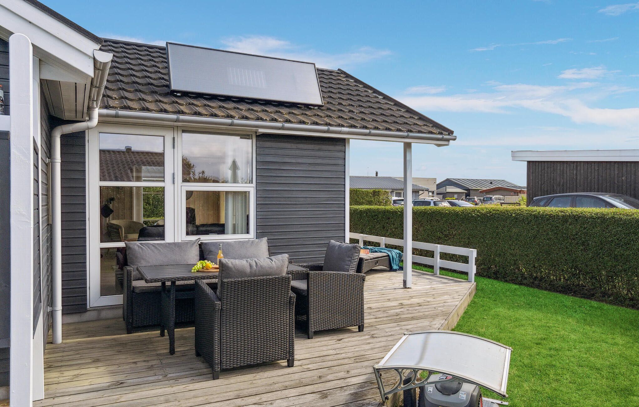 Un patio techado al aire libre con mobiliario de mimbre, una mesa y una silla.