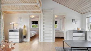 Un dormitorio moderno de planta abierta con cama estilo loft, un escritorio y una zona de comedor.