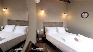 Ein Hotelzimmer mit zwei Betten, einem Holzkopfstück, Nachttischlampen, einem kleinen Tisch und einer Fernbedienung auf dem Boden.
