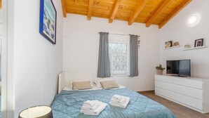 Une chambre à coucher avec un lit, une télévision, une commode et un tableau accroché au mur.