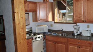 A compact kitchen with wooden cabinets, a stove, a microwave, a sink, and a coffee maker. - Dog Friendly Creekside Property close to Vallecito Lake minutes to Durango (Bayfield)
