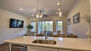 A modern kitchen with a large island, stainless steel appliances, and pendant lighting.