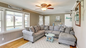 A living room with a sectional sofa, a small table, and a ceiling fan.