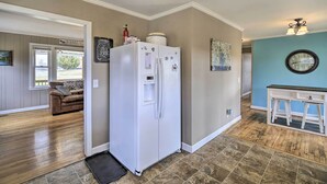 A kitchen with a white refrigerator, wooden flooring, and a dining area with a table and chairs.