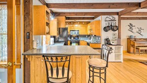 Una cocina con armarios de madera, encimera de granito y una isla central con dos taburetes de bar.