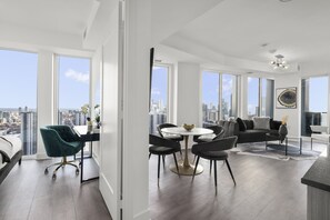 Enjoy panoramic city views from the spacious living area with a dining table and comfortable seating.