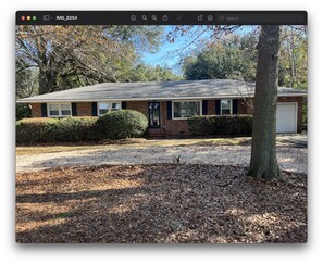 Stunning home with a brick facade, front door, windows, and garage door, set amidst a beautifully manicured lawn and tree.