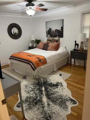 Cozy retreat with a neatly made bed, wall-mounted mirror, and a bedside table with a lamp.