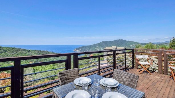 A dining area with a table set for four, overlooking a coastal landscape with hills and the sea. - 3 bedroom stunning home in Moneglia (Moneglia)