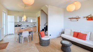 A modern living room with a sofa, chairs, a dining table, and a kitchen in the background. - 3 bedroom stunning home in Moneglia (Moneglia)