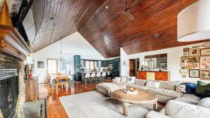 A spacious living area with a fireplace, a dining table, and a kitchen in the background. - Cabin w/ Mountain Views, Hot Tub, AC, Pet + Family Friendly, WFH, Fireplace (Lexington)