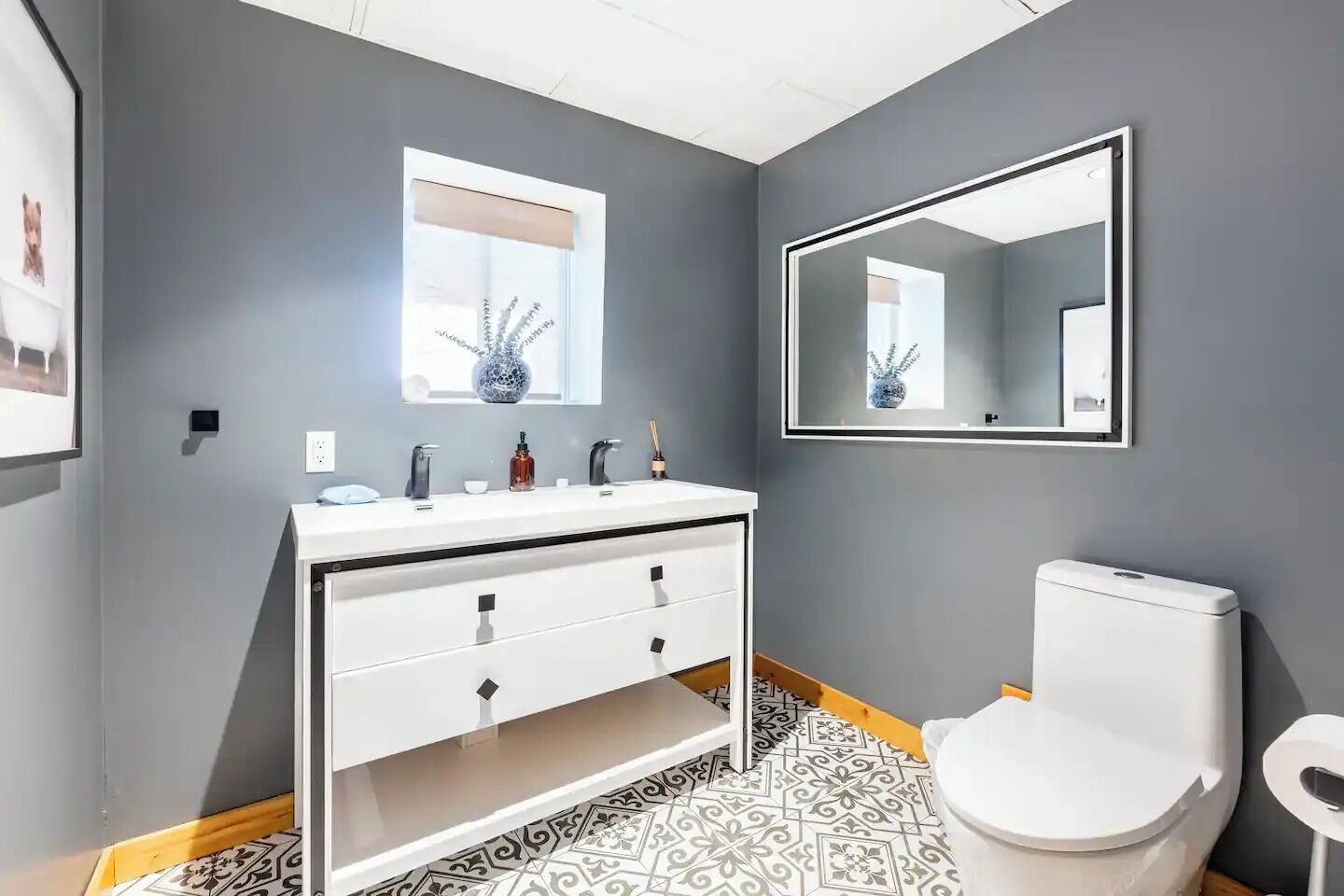 A modern bathroom with a white vanity, a large mirror, and a toilet.