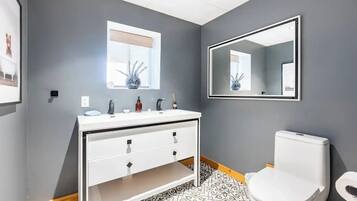 A modern bathroom with a white vanity, a large mirror, and a toilet.