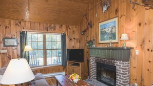 A cozy cabin interior with a wooden interior, a fireplace, a television, and a comfortable seating area. - Bayberry Cottage  (Lexington)