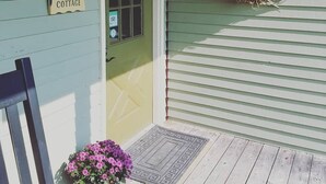 A green door with a 'Welcome to Bayberry Cottage' sign, a potted purple flower, and a wreath on the wall. - Bayberry Cottage  (Lexington)