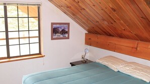 A bedroom with a bed, a nightstand, a picture on the wall, and a window with a view of trees. - Dog Friendly Creekside Property close to Vallecito Lake minutes to Durango and so much adventure out the front door (Bayfield)