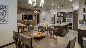 Una cocina moderna con una isla central, electrodomésticos de acero inoxidable y un comedor con mesa y sillas de madera.