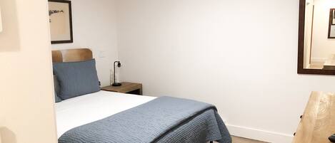 A bedroom with a bed, a nightstand, a lamp, a rug, and a wooden cabinet.