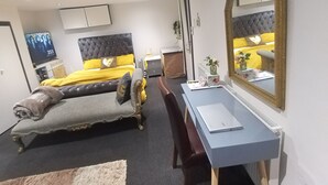 A bedroom with a bed, a desk, a chair, a mirror, and a television.