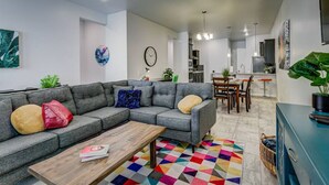A modern living room with a grey sectional sofa, a wooden coffee table, and a colorful geometric rug. - 4010 · Comfortable New Home with community pool and golf (Las Cruces)