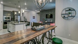 Una cucina moderna con elettrodomestici in acciaio inossidabile, un'isola in legno e un originale lampadario.