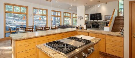 A spacious kitchen with a large island, wooden cabinets, and a stone backsplash.