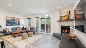 A spacious living room with a fireplace, a sofa set, and a large painting. - Bear Creek Lodge 207 2 Bedroom Condo by Alpine Lodging Telluride (Telluride)