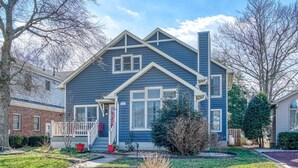 A two-story house with a front porch, a chimney, and a well-maintained front yard with a small tree and shrubs. - Family Tides - 311 139th Street 4 Bedroom Home by RedAwning (Ocean City)