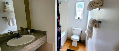 A bathroom with a sink, toilet, and shower area.