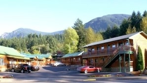 A lodge with a green roof, a staircase leading to a balcony, and a mountain backdrop. - Bridge of The Gods (Cascade Locks)