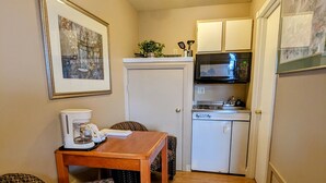 A compact living space with a kitchenette, a dining area with a table and chairs, and a patterned sofa. - Bridge of The Gods (Cascade Locks)