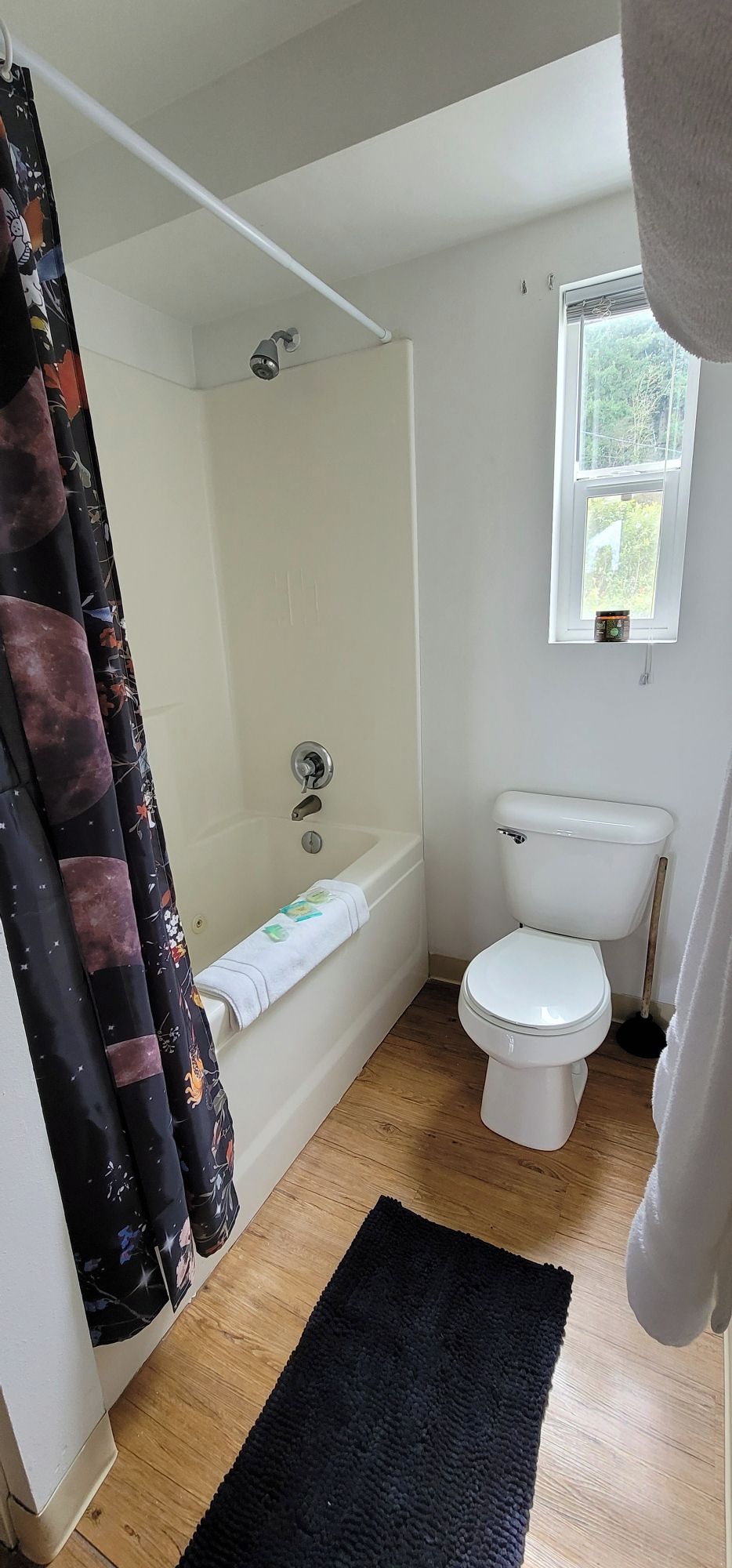 A bathroom with a bathtub, toilet, and a window.