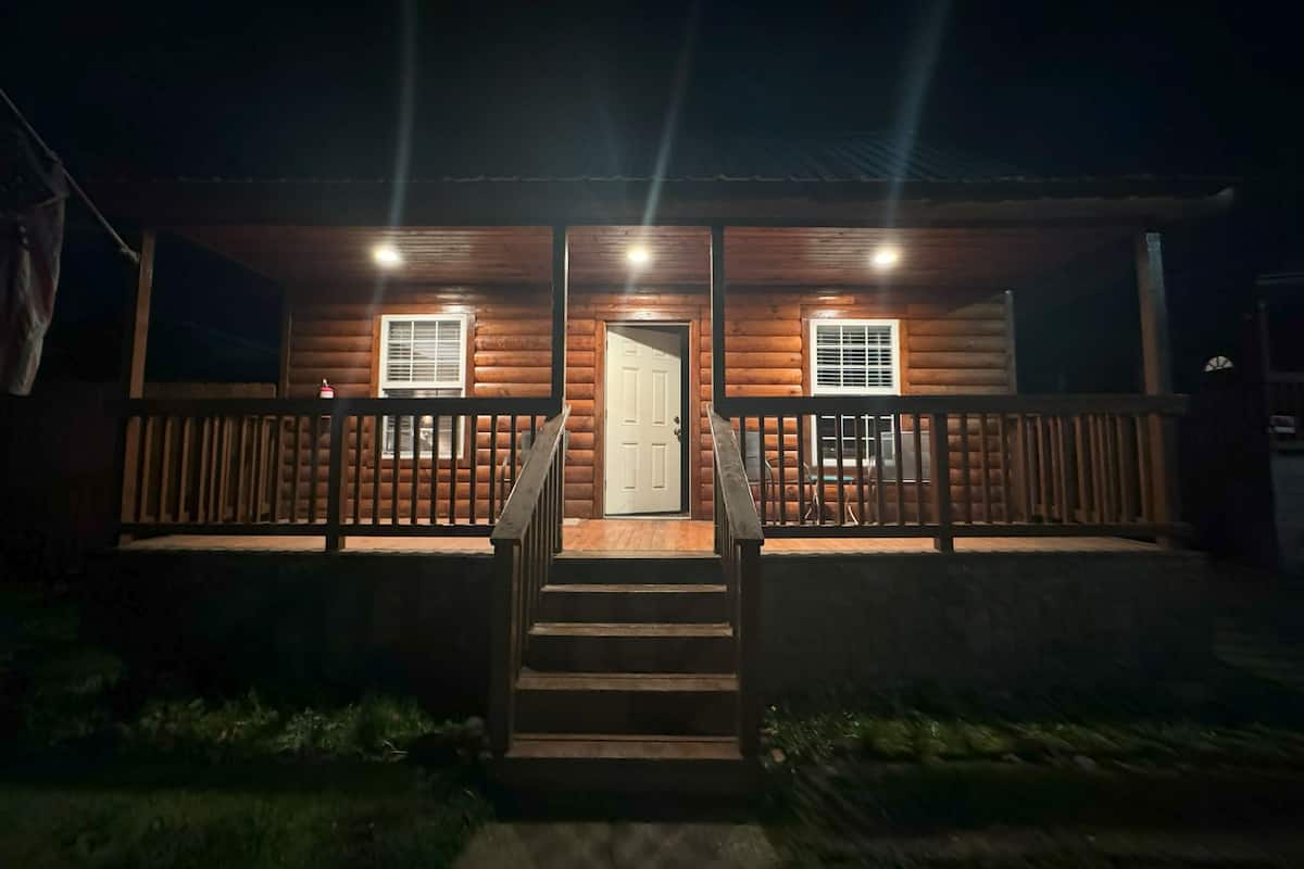 Eine Holzhütte mit Veranda, zwei Fenstern und einer Tür.