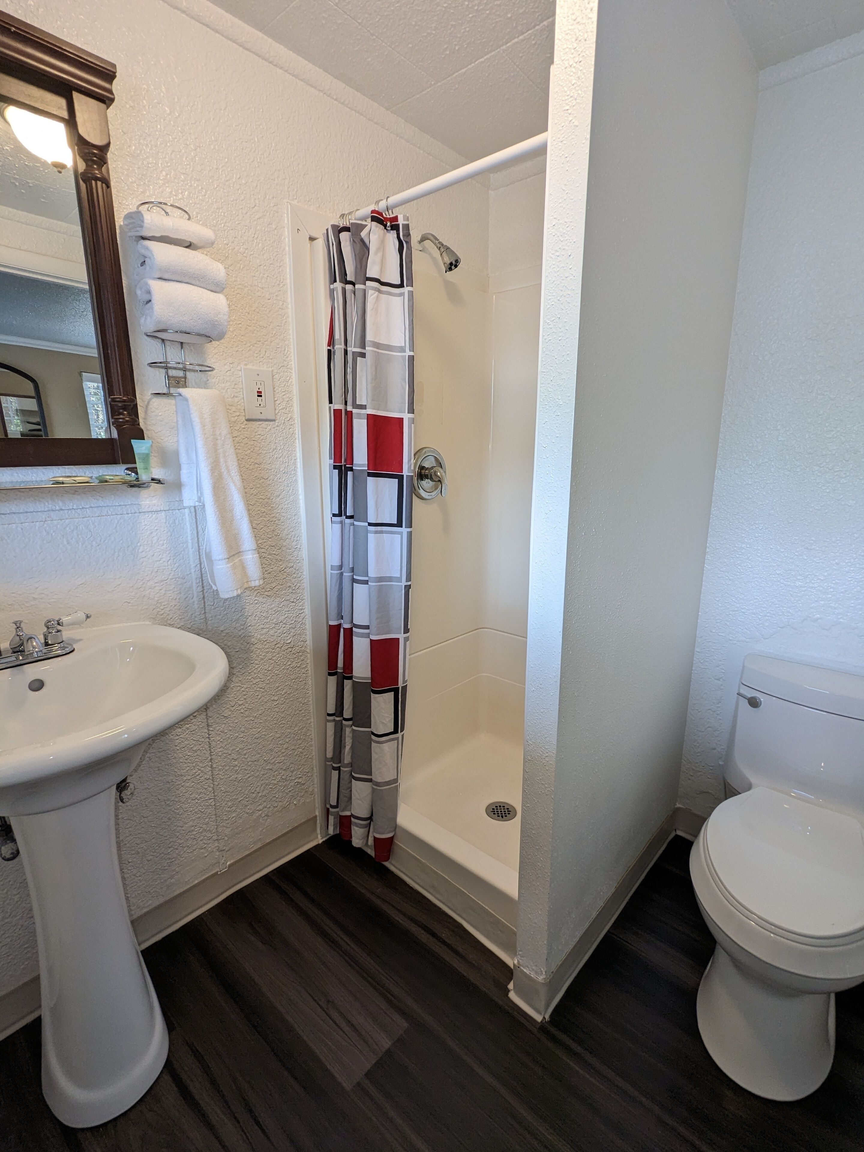 Ein Badezimmer mit Dusche, Toilette, Waschbecken und Spiegel.