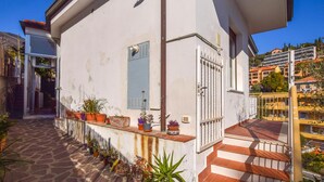 A white building with a balcony, potted plants, and a view of a hillside with other buildings. - Gorgeous apartment in Alassio with WiFi (Alassio)