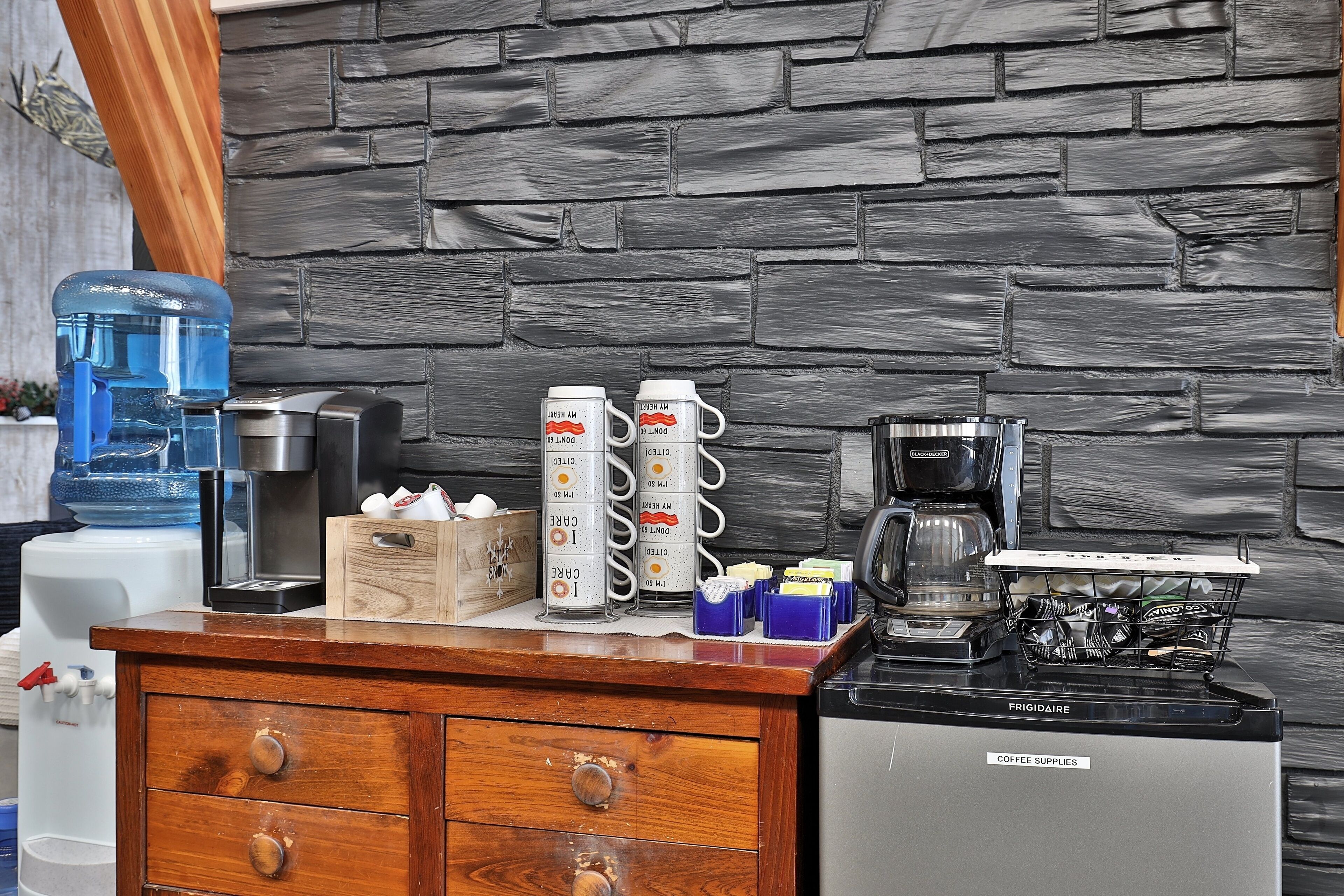 A kitchen counter with a coffee maker, water dispenser, and storage containers.