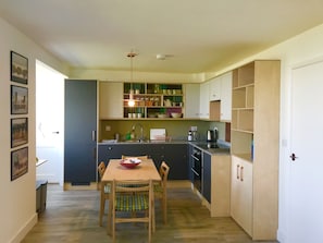 A compact kitchen with a dining table, chairs, and a variety of cabinets and shelves.