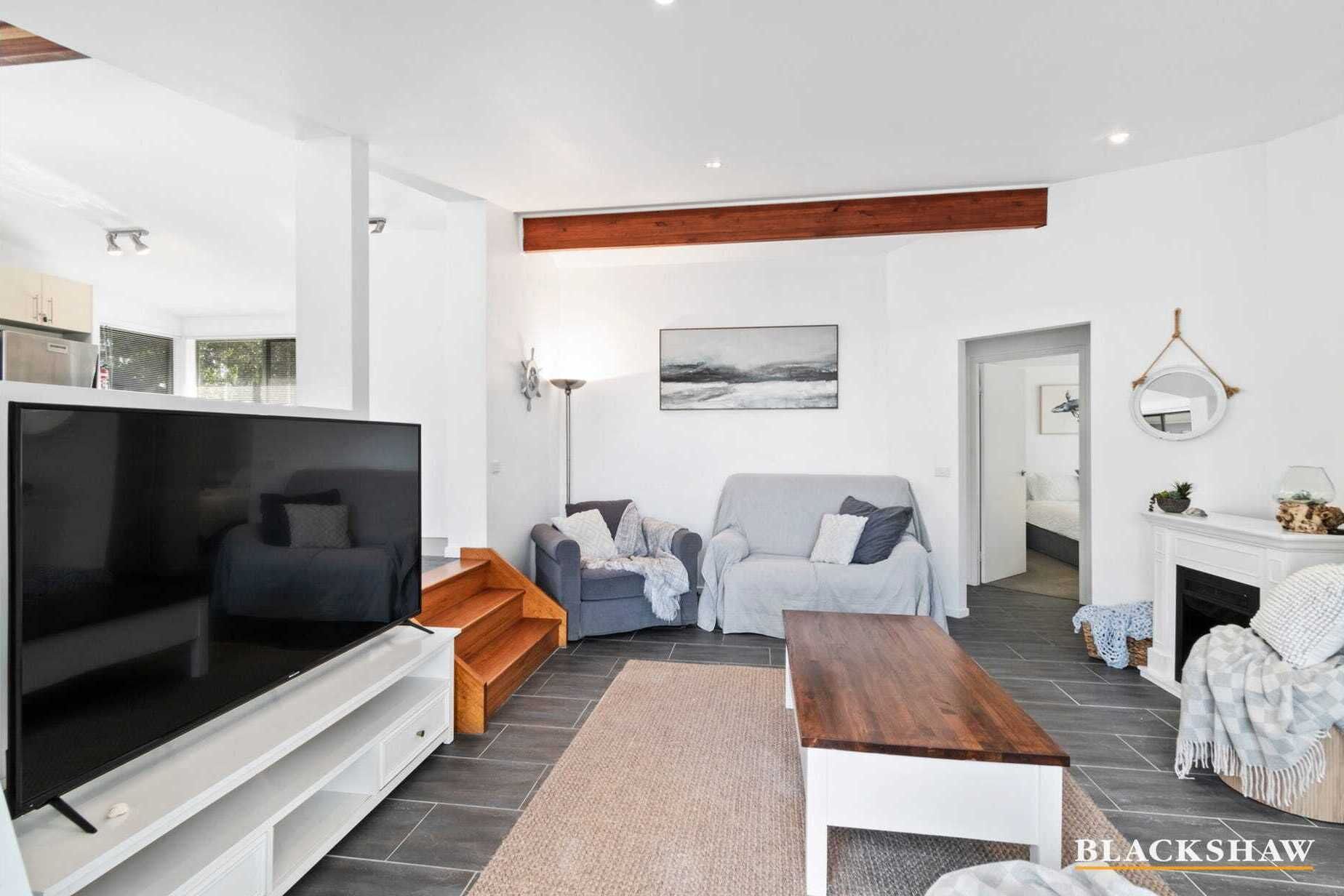 Een moderne woonkamer met een flatscreen televisie, twee banken, een houten salontafel en een open haard.