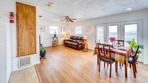 A spacious living area with a wooden floor, a leather sofa, a dining table set for four, and a ceiling fan. - Corpus Christi Extended Stay - 7 Mi to Beach! (Corpus Christi)