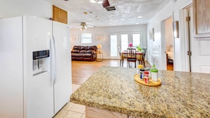 A spacious kitchen with a granite countertop, a white refrigerator, and a dining area with a table and chairs. - Corpus Christi Extended Stay - 7 Mi to Beach! (Corpus Christi)