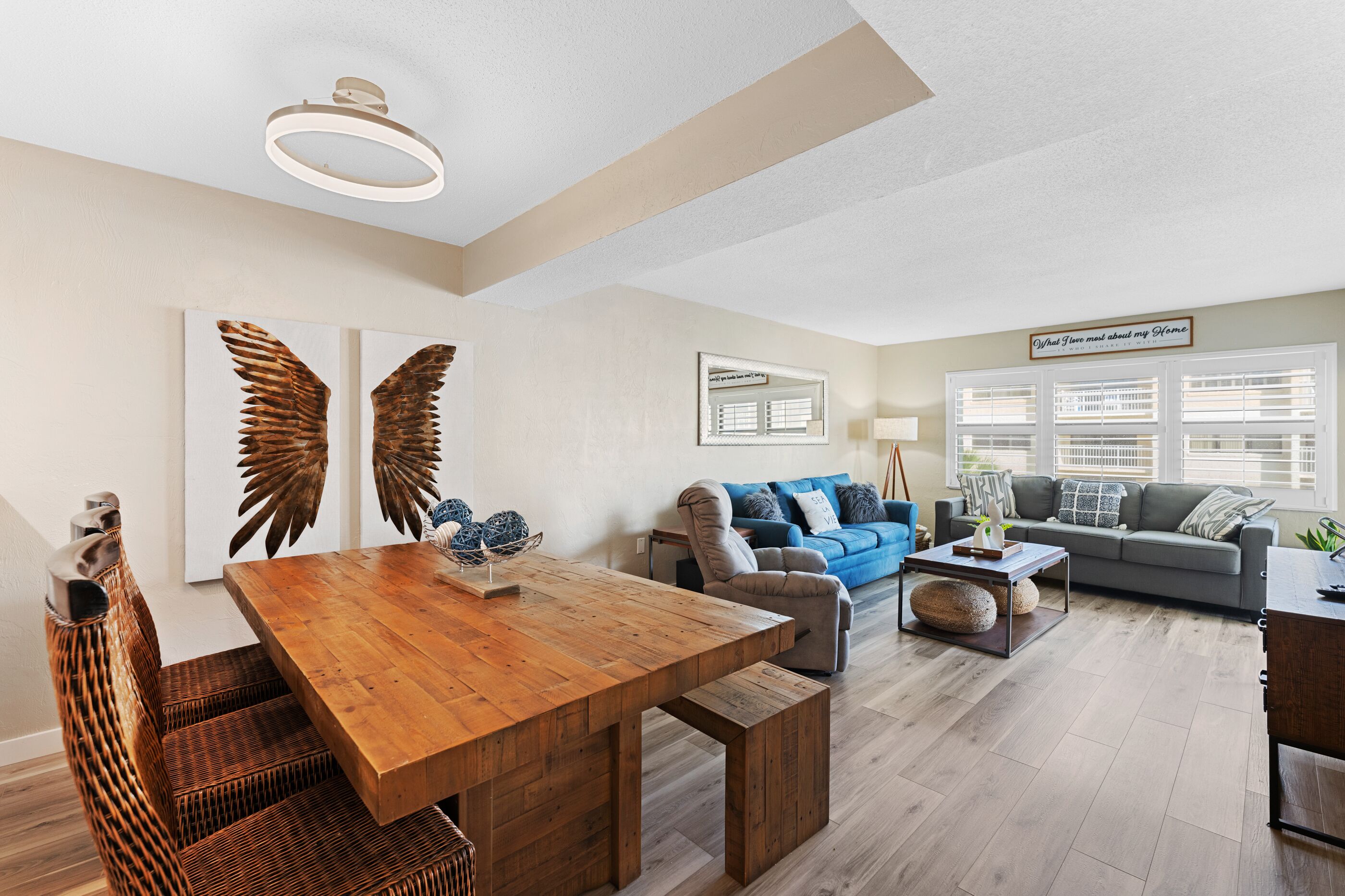 Amplia sala de estar con una mesa de comedor de madera, un sofá azul y un sofá gris.