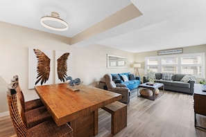 A spacious living area with a wooden dining table, a blue sofa, and a gray couch.