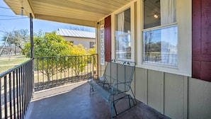 A covered porch with a metal bench, a 'WELCOME' sign, and a view of the surrounding area. - Charming Home Near Downtown Fredericksburg! (Fredericksburg)